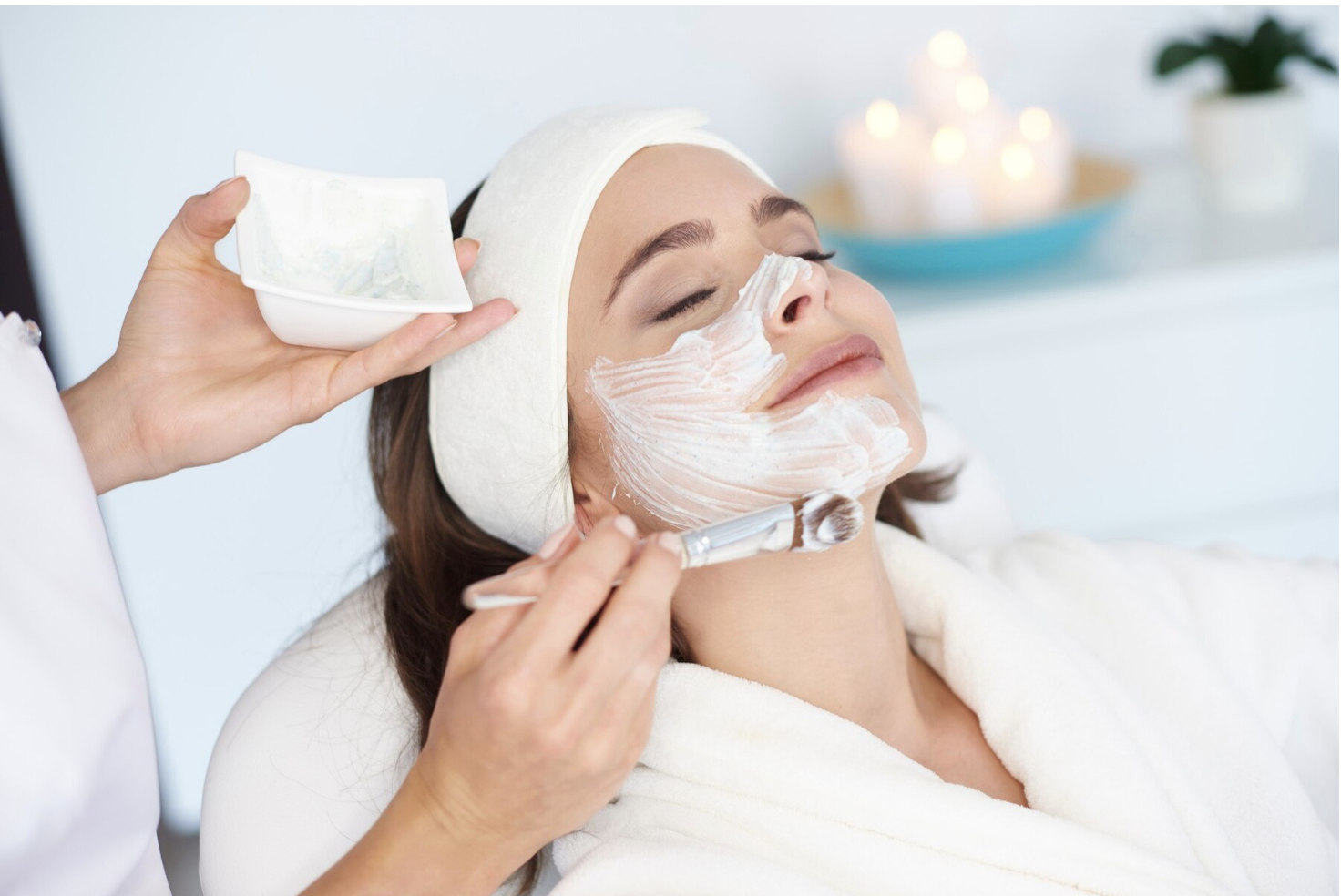 a woman is receiving a radiance facial in the spa. The tech is applying the facial with a soft brush