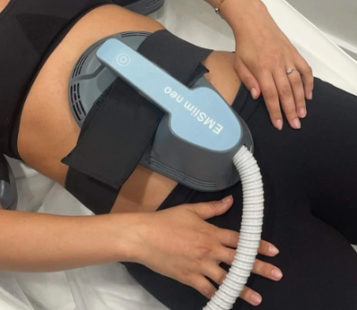 Close-up of an EMslim neo applicator placed on a woman's abdomen during a body contouring treatment